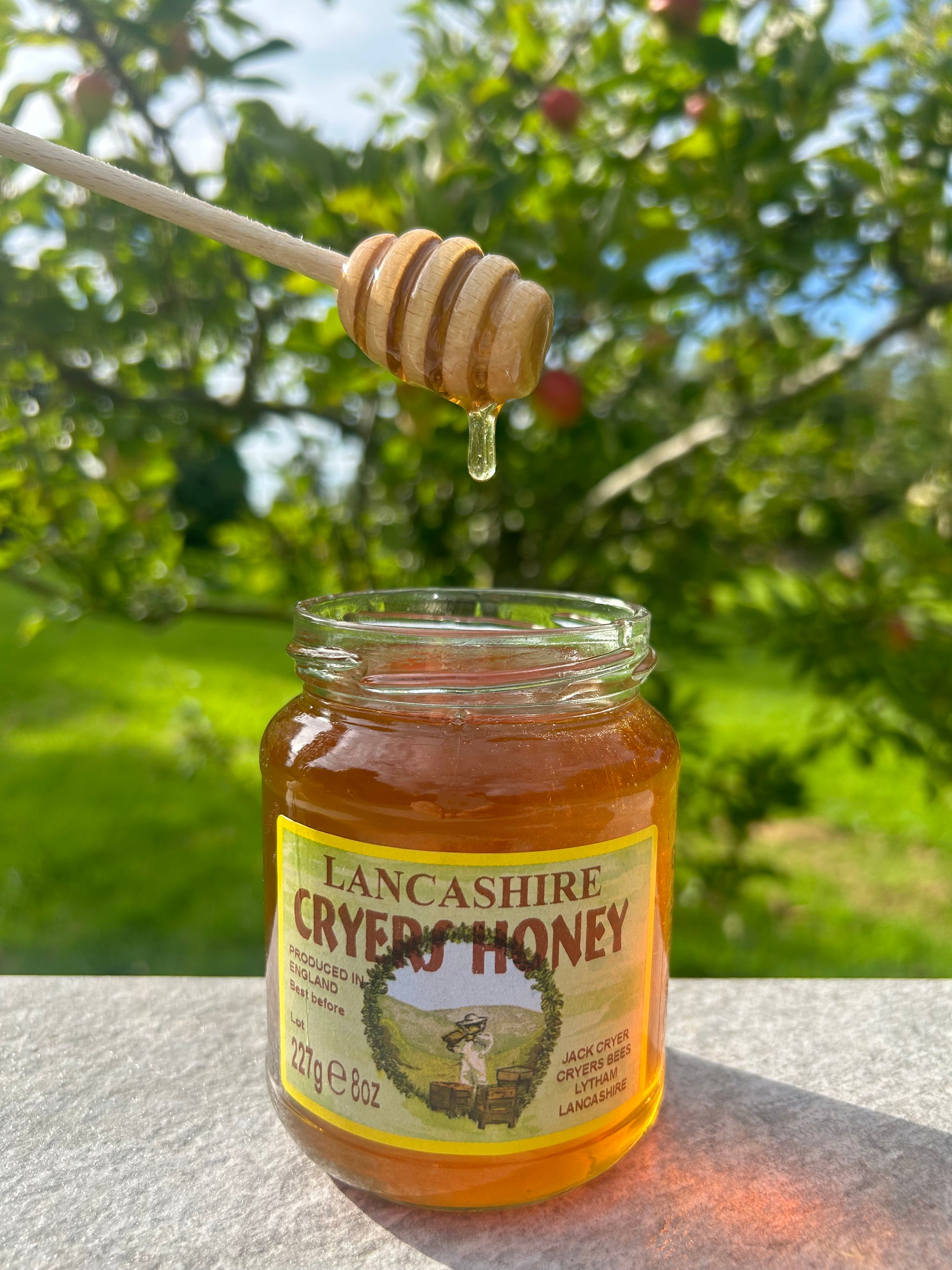 Lancashire Honey being drizzled from a dipper, highlighting the smooth and rich texture of the honey.