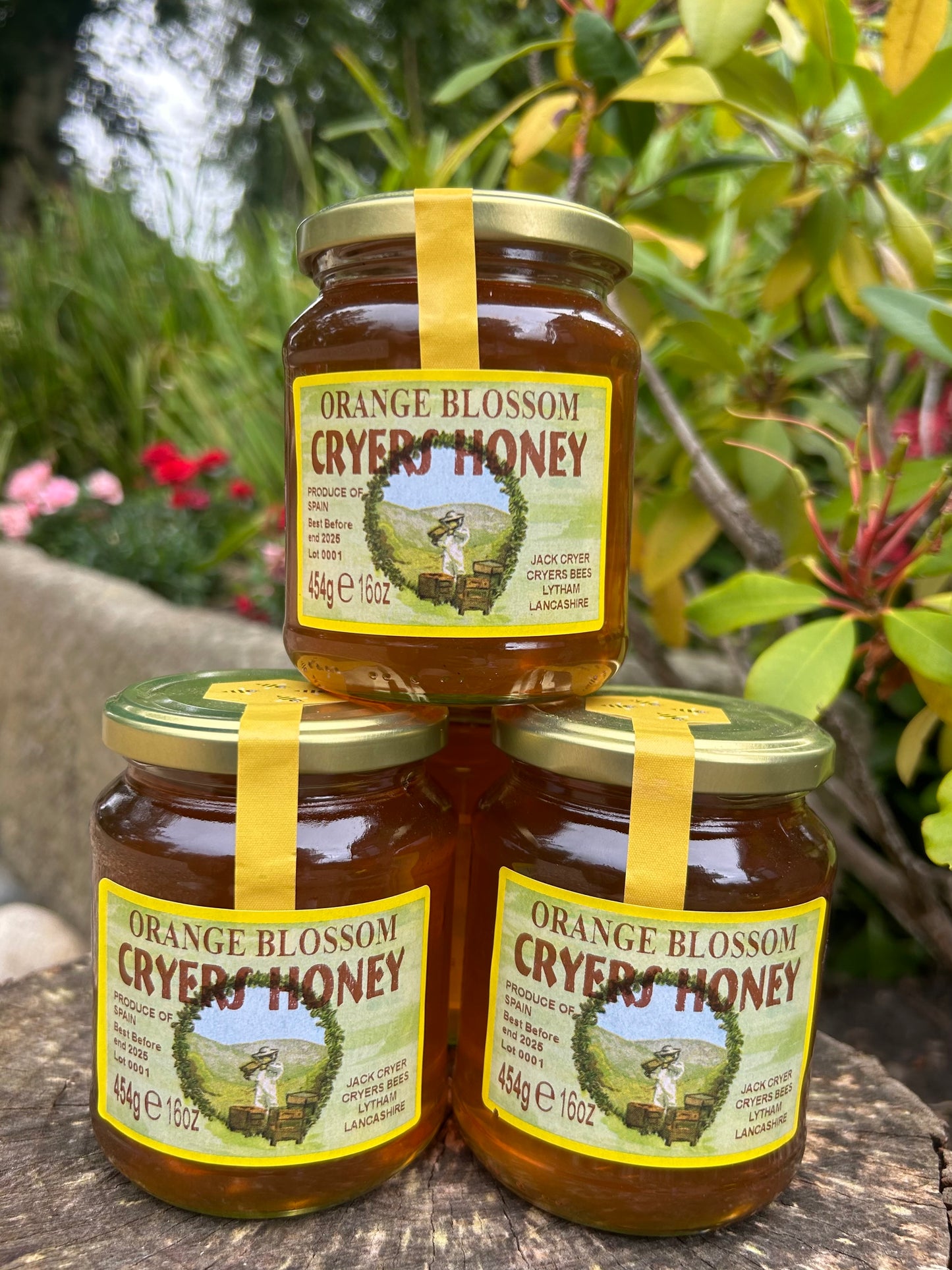 Stack of Cryer’s Orange Blossom Honey jars displayed outdoors.